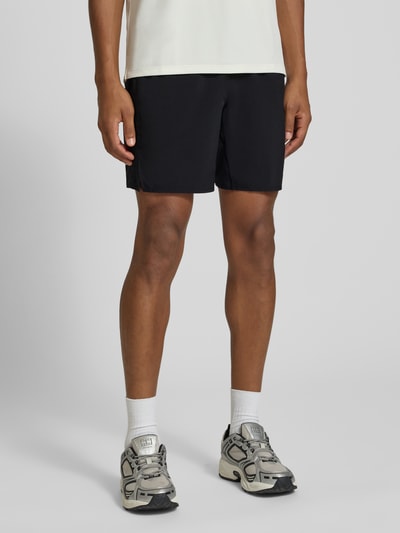 Männermodel trägt schwarze Shorts mit elastischem Bund und Logo von ASICS, Regular Fit, Nahaufnahme Oberschenkel bis Knie, Kontext Herren Shorts