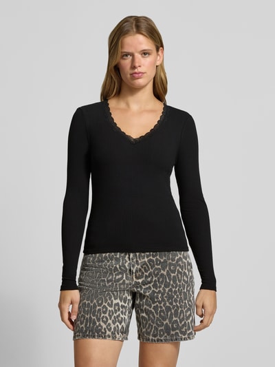 Frauenmodel trägt schwarzes Slim Fit Langarmshirt aus Baumwoll-Mix Modell 'SARA SHARAI' von ONLY, dezente Struktur, Ganzkörperansicht von vorne, Damen Langarmshirt von ONLY.
