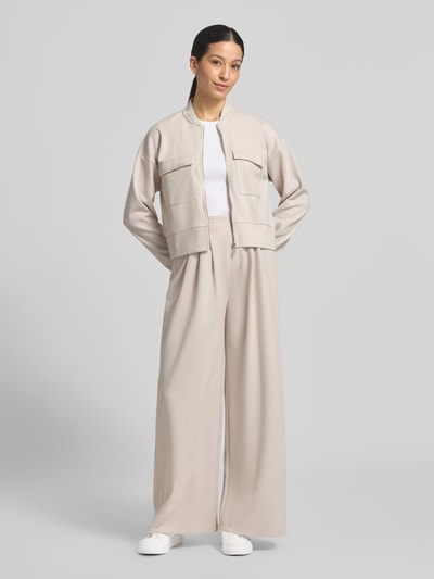 Kobiece model prezentuje Wide Fit Stoffhose mit gelegten Falten von Christian Berg Woman, jasny beż, bawełniany miks, widoczna tekstura, szeroki krój, elastyczny pas, Ganzkörperansicht von vorne.