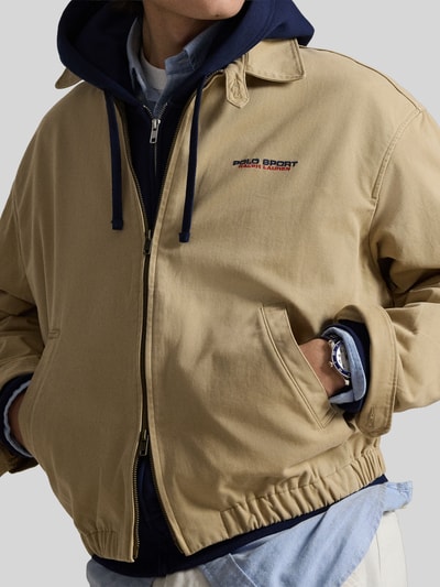 Männermodel trägt Regular Fit Blouson aus reiner Baumwolle von Polo Ralph Lauren in Beige, Zweiwege-Reißverschluss, Label Stitching, Nahaufnahme Oberkörper.