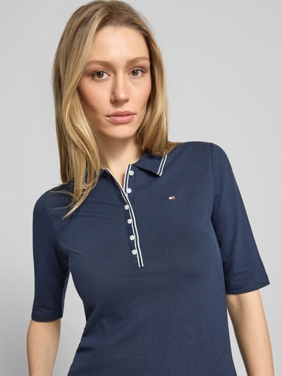 Frauenmodel trägt Slim Fit Poloshirt aus Lyocell-Mix von Tommy Hilfiger, Optik: Unifarben, Logo-Stitching, Kontraststreifen, 1/2-Arm, Materialverarbeitung: Piqué, Nahaufnahme Oberkörper.