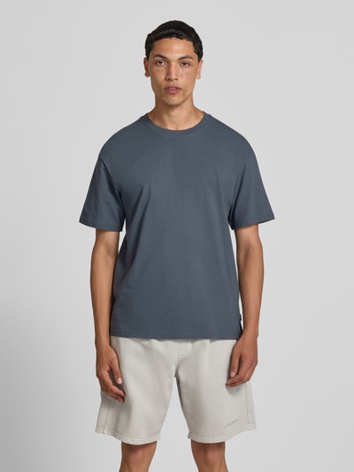 Męski model nosi Regular Fit T-Shirt mit Rundhalsausschnitt von Jack & Jones, bawełna, krój regular fit, okrągły dekolt, rękaw o dł. 1/2, długość tyłu w rozmiarze M: 70 cm, kolor ciemnoszary, prosta faktura, gładki materiał. Ganzkörperansicht von vorne.