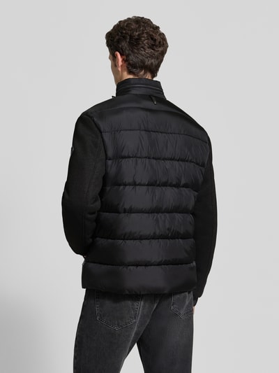 Männermodel trägt Regular Fit Steppjacke mit Stehkragen Modell 'Ciscos' von JOOP! COLLECTION in Schwarz, Ganzkörperansicht Rückansicht.