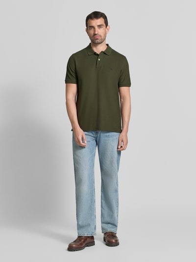 Männermodel trägt Regular Fit Poloshirt mit Label-Stitching von Fynch-Hatton in Olivgrün, reine Baumwolle, Knopfleiste, Ganzkörperansicht von vorne