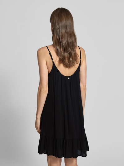 Frauenmodel trägt Minikleid aus Viskose mit tiefem Rückenausschnitt von Shiwi in Schwarz, A-Linie, Modell 'Ibiza Dress Solid', Rückenansicht, Ganzkörperansicht.