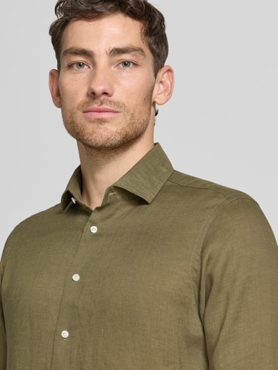 Männermodel trägt Regular Fit Leinenhemd mit Kentkragen von Christian Berg Men in Olivgrün, feine Webstruktur, Nahaufnahme Oberkörper.