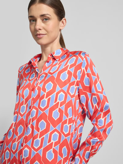 Vrouwenmodel draagt Slim Fit Hemdbluse aus reiner Viskose van Milano Italy met rood-blauw grafisch patroon, doorlopende knoopsluiting, overhemdkraag, zuiver viscose, slim fit pasvorm, blouse met lange mouwen, ruglengte 65 cm maat 36, mouwlengte 62 cm maat 36. Nahaufnahme bovenlichaam.