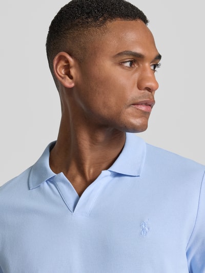 Męski model nosi Slim Fit Poloshirt aus Baumwoll-Mix von Polo Ralph Lauren, jednolity kolor, detal z logo, dekolt w serek, pika, mieszanka bawełny, krótki rękaw, kołnierzyk polo. Zbliżenie na górną część ciała