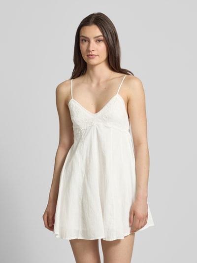 Frauenmodel trägt Minikleid aus reiner Baumwolle Modell 'PANOLA' von Only, Optik: Unifarben, tailliert, V-Ausschnitt, Smok-Einsatz, Stickerei, verstellbare Spaghettiträger, Mini-Länge, Ganzkörperansicht von vorne.
