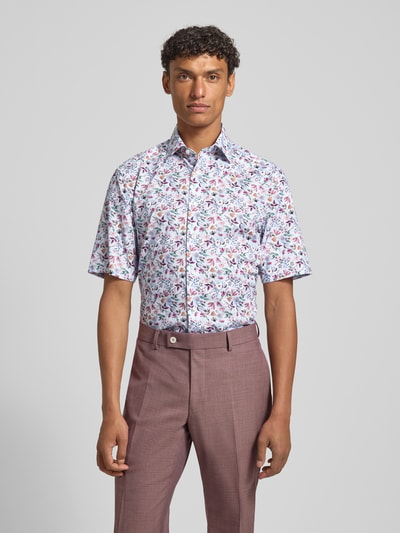 Männermodel trägt Regular Fit Business-Hemd mit floralem Muster und Kentkragen von OLYMP, weiße Grundfarbe, bunte Blumen, Nahaufnahme Oberkörper, reine Baumwolle