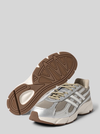 Produktfoto, Sneaker mit Schnürverschluss von adidas Sportswear in Silber und Beige, Material-Mix, strukturierte braune Sohle, Label-Detail sichtbar.