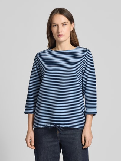 Frauenmodel trägt Regular Fit 3/4-Shirt aus Bio-Baumwoll-Mix von Tom Tailor mit blauem Allover-Streifenmuster, Rundhals, Knöpfe am Kragen, 3/4-Ärmeln, Rippstruktur, Tunnelzug am Saum, Ganzkörperansicht von vorne.