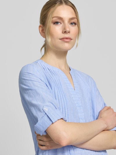 Frauenmodel trägt Tunikakleid mit Volantsaum und Tunikakragen von Milano Italy aus reiner Baumwolle in Hellblau mit feinen Streifen, Nahaufnahme Oberkörper.