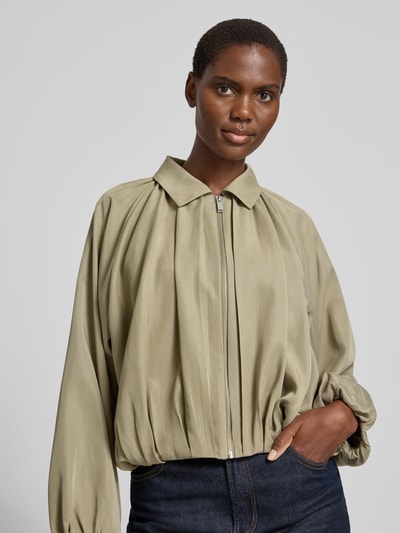 Frauenmodel trägt Jacke aus Lyocell mit Reißverschluss Modell 'Jabana' von OPUS in hellem Olivgrün, Umlegekragen, Relaxed Fit, Nahaufnahme Oberkörper.