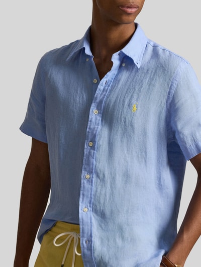 Mannenmodel draagt Regular Fit Leinenhemd mit Button-Down-Kragen van Polo Ralph Lauren, look: effen kleuren, regular fit pasvorm, button-downkraag, doorlopende knoopsluiting, gestikt logo, korte mouw, licht afgeronde rompzoom, materiaal: puur linnen. Close-up van de bovenlichaam.