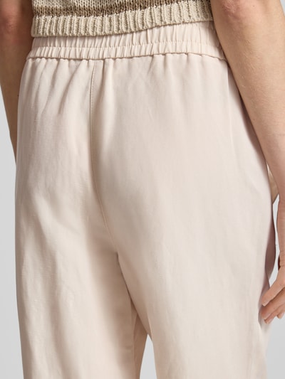 Kobieta nosi Leinenhose mit elastischem Bund Modell 'Roma' od STEHMANN, len, spodnie z szerokimi nogawkami, elastyczny pas, szerokość w rozmiarze 36: 39 cm, długość wewnętrzna nogawki w rozmiarze 36: 81 cm, jasny beż, gładka faktura, detal tyłu, zbliżenie na biodra.
