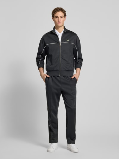 Männermodel trägt Regular Fit Sweatjacke mit Baumwoll-Anteil von Lacoste in Optik: Unifarben, Kontraststreifen, Logo-Detail, Ganzkörperansicht von vorne.