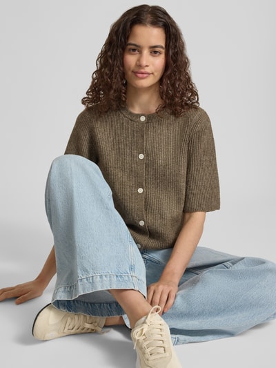 Frauenmodel trägt Boxy Fit Strickjacke aus Rippstrick Modell 'SILLY' von PIECES in Melange-Optik, Knopfleiste, kurzarm, Nahaufnahme Oberkörper.