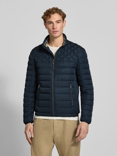 Männermodel trägt Steppjacke mit Stehkragen und Reißverschlusstaschen von Christian Berg Men in Dunkelblau, Ganzkörperansicht von vorne. Regular Fit, sichtbarer Reißverschluss, Reißverschlusstaschen, Rückenlänge 68 cm, Schulterbreite 48 cm, Brustweite 60 cm, Ärmellänge 69 cm.