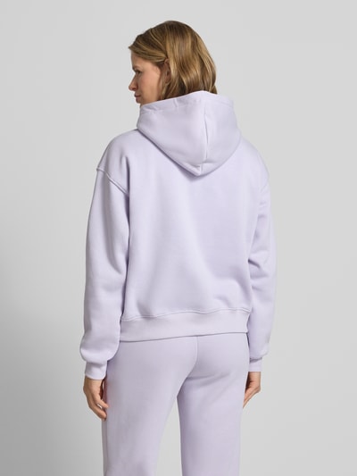 Frauenmodel trägt Hoodie mit Känguru-Tasche Modell 'Iconic' von Gina Tricot, bawełniany miks, krój relaxed fit, widok całej sylwetki z tyłu