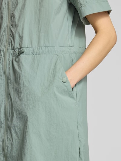 Kobieta nosi Knielanges Kleid mit Zweiwege-Reißverschluss Modell 'RONNY2' od FIRE + ICE, prosty krój, długość do kolan, kaptur, zamek dwukierunkowy, długość pleców w rozmiarze 36: 96 cm, szerokość w rozmiarze 36: 49 cm, długość rękawa w rozmiarze 36: 21 cm, miękka tekstura, kolor jasnozielony, detal kieszeni, zbliżenie na górną część ciała