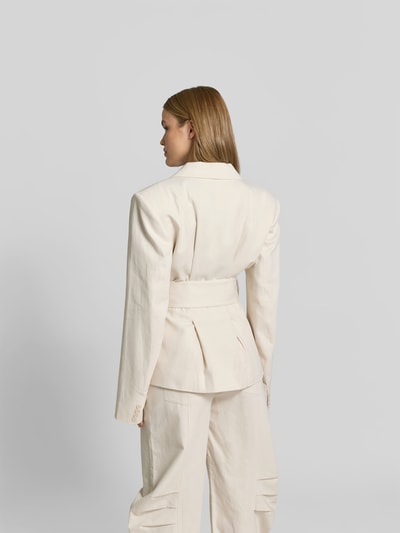 Frauenmodel trägt Blazer aus Leinen-Mix mit Taillen-Gürtel von ROTATE in Creme, strukturierte Oberfläche, Reverskragen, Ganzkörperansicht Rückansicht.