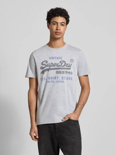 Męski t-shirt od Superdry Relaxed Fit T-Shirt mit Logo-Stitching Modell 'Heritage' z mieszanki bawełny, szary z wyhaftowanym logo, okrągły dekolt, długość tyłu w rozmiarze M: 71 cm, Ganzkörperansicht von vorne.