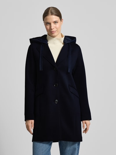 Kobiece model prezentuje Płaszcz mit Kapuze und Pattentaschen od Christian Berg Woman Selection, mieszanka materiałów z dodatkiem wiskozy, krój regular fit, kaptur z tunelem, listwa guzikowa, kieszenie z patką, długość tyłu w rozmiarze 36: 88 cm, szerokość ramion w rozmiarze 36: 45 cm, szerokość w rozmiarze 36: 50 cm, długość rękawów w rozmiarze 36: 57 cm, granatowy, gładka faktura, widok na cały przód.