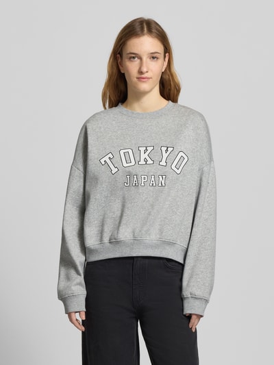 Modelka kobieca ma na sobie szary Oversized Sweatshirt aus Baumwoll-Mix Modell 'SWEAT LIFE' od Only, motyw nadruk, długi rękaw, widok z przodu na całe ciało.