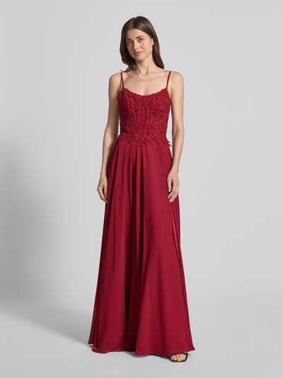 Kobiece model prezentuje wieczorową suknię z koronkową aplikacją 'Abendkleid mit floralem Spitznbesatz' od Mascara, w kolorze bordowym, krój slim fit, ozdobna koronka z kamieniami, cienkie ramiączka, dekolt carmen, spódnica szyfonowa, kryta halka, zamek w szwie, sznurowanie z tyłu, długość pleców w rozmiarze 36: 152 cm, szerokość w rozmiarze 36: 40 cm, pełny widok z przodu.