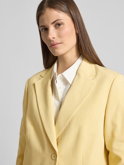 Vrouwenmodel draagt Relaxed Fit Blazer mit Pattentaschen van Scotch & Soda in lichtgeel, mix van katoen en lyocell, reverskraag, knoopsluiting, klepzak, borstwijdte 42 cm, mouwlengte 62 cm, ruglengte 74 cm, Nahaufnahme Oberkörper.