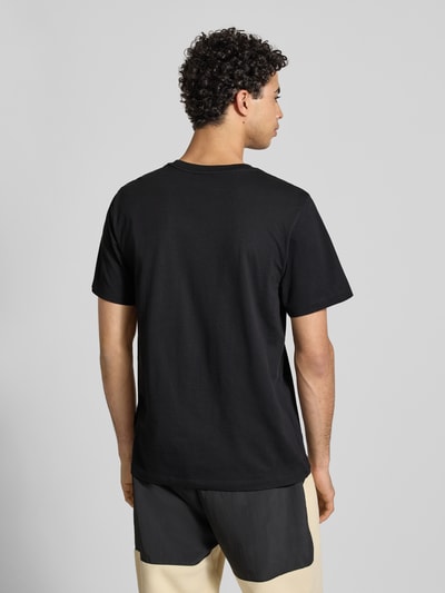 Männermodel trägt Regular Fit T-Shirt aus Baumwoll-Mix Modell 'EVOLUTION' von The North Face, schwarze Farbe, Rückenlänge 71 cm, Ganzkörperansicht Rückansicht.