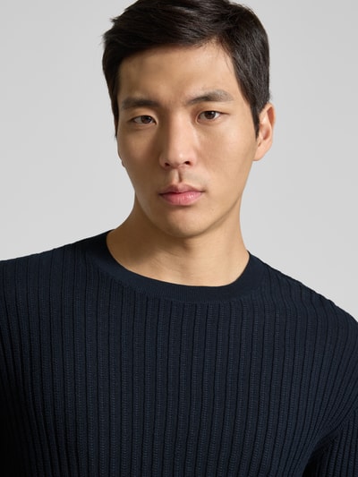Männermodel trägt Slim Fit Pullover in Strick-Optik von Armani Exchange aus reiner Baumwolle, Rundhalsausschnitt, Nahaufnahme Oberkörper.