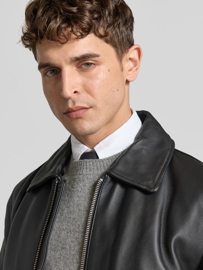 Männermodel trägt Kunstlederjacke mit Kontrastkragen aus Teddyfell von Moose Knuckles, mattschwarze Optik, strukturierter Kragen, Nahaufnahme Oberkörper.