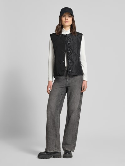 Vrouwenmodel draagt Regular Fit Bodywarmer met een rij knopen Model 'MILLIE' van Vero Moda, look: effen, met steekzakken, doorgestikt materiaal, full body aanzicht vooraan.