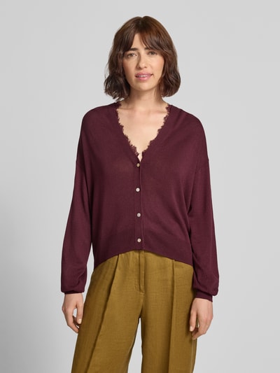 Modelka nosi kardigan mit V-Ausschnitt und Spitzenbesatz von Jake*s Casual, Mieszanka materiałów z lnem, krój regular fit, dekolt w serek, obszycie koronką, listwa guzikowa, długość tyłu w rozmiarze S: 55 cm, długość rękawów w rozmiarze S: 49 cm, kolor bordowy, prosta tekstura, widok całej sylwetki z przodu.