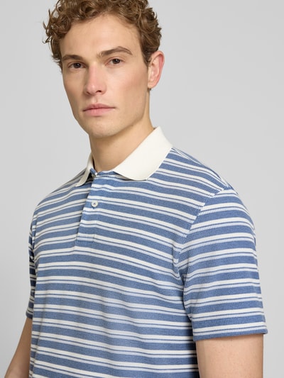 Männermodel trägt Regular Fit Poloshirt aus Baumwoll-Mix Modell 'BLAZE' von SELECTED HOMME, blau gestreift, Struktur Piqué, Nahaufnahme Oberkörper.