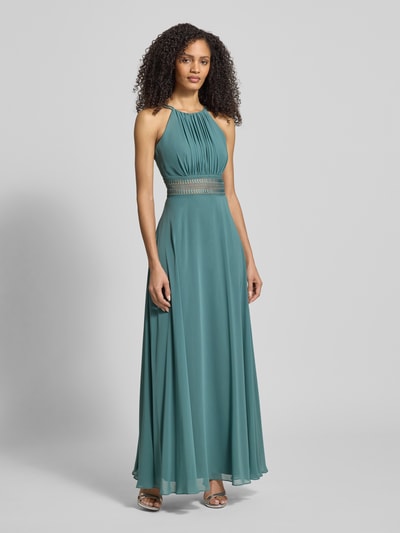 Frauenmodel trägt Abendkleid mit Raffungen von Jake*s Cocktail, taillierter Schnitt, Spaghettiträger, blickdichtes Unterkleid, Nahtreißverschluss, smaragdgrüne Farbe, fließender Stoff, Ganzkörperansicht von vorne.