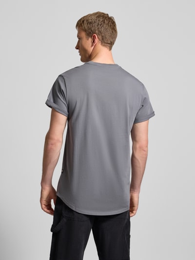 Männermodel trägt T-Shirt mit Label-Detail von G-Star aus reiner Bio-Baumwolle, gerader Schnitt, fixierte Ärmelumschläge, Ganzkörperansicht Rückansicht.