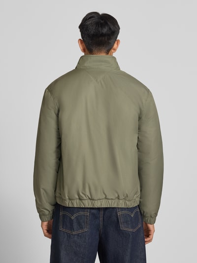 Männermodel trägt Regular Fit Blouson mit Label-Patch von Tommy Jeans, olivgrün, glatte Oberfläche, Herren Bomberjacke, Ganzkörperansicht Rückansicht.