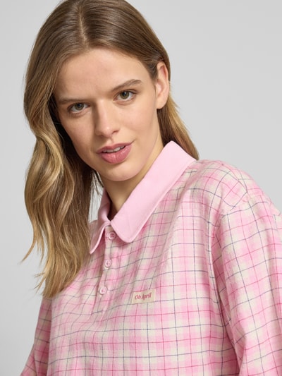 Frauenmodel trägt Oversized Poloshirt mit Label-Detail Modell 'Diana' von OH APRIL in Rosa-Karomuster, Reine Baumwolle, Longsleeve, Nahaufnahme Oberkörper.