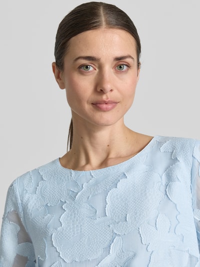 Frauenmodel trägt Blusenshirt aus Viskose-Mix mit Strukturmuster von More & More, hellblau, Rundhalsausschnitt, Nahaufnahme Oberkörper.