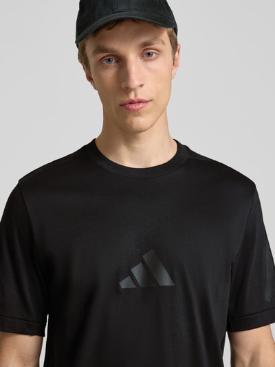 Männermodel trägt Regular Fit T-Shirt aus reiner Baumwolle von adidas Sportswear, efekt: jednolity kolor, krój regular fit, nadruk z logo, okrągły dekolt, rękaw: krótki rękaw, materiał: bawełna, Nahaufnahme Oberkörper.