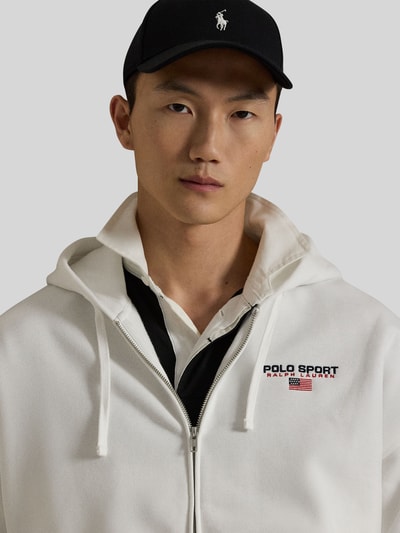 Männermodel trägt Relaxed Fit Sweatjacke aus Baumwoll-Mix von Polo Ralph Lauren in Weiß, Label-Schriftzug, Kapuze, Nahaufnahme Oberkörper.