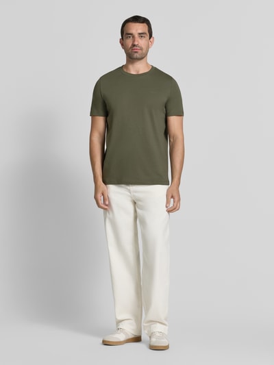 Męski model nosi Regular Fit T-Shirt aus reiner Baumwolle od s.Oliver RED LABEL, oliwkowy, biały, t-shirt, spodnie, buty, gładka faktura, Ganzkörperansicht von vorne.