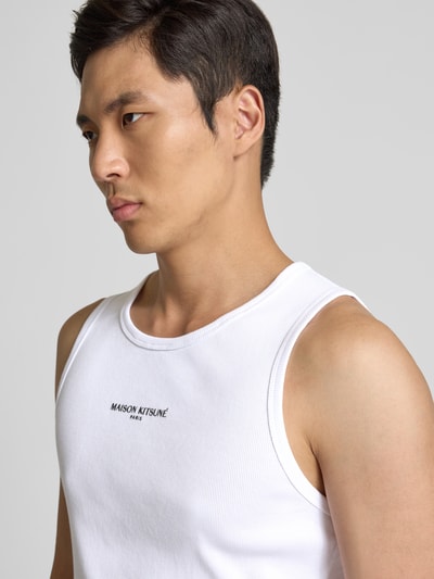 Männermodel trägt Top aus reiner Baumwolle von MAISON KITSUNÉ in Weiß mit Ripp-Optik und Label-Detail, Nahaufnahme Oberkörper.