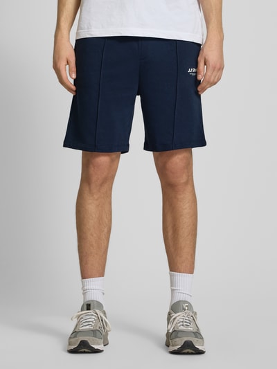 Männermodel trägt Sweatshorts mit Logo Modell 'KANE' von Jack & Jones in Dunkelblau, Baumwoll-Mix, Relaxed-Fit, Ganzkörperansicht von vorne.