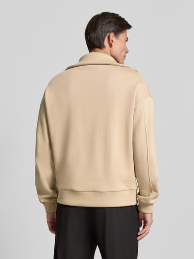 Męski model nosi Regular Fit Sweatshirt aus Baumwoll-Mix mit Troyer-Kragen od DRYKORN, mieszanka bawełny, krój regular fit, kołnierz zapinany, wyhaftowane logo, Długość tyłu w rozmiarze M: 64 cm, Długość rękawów w rozmiarze M: 57 cm, beżowy kolor, miękka tekstura, widok całej sylwetki z tyłu.