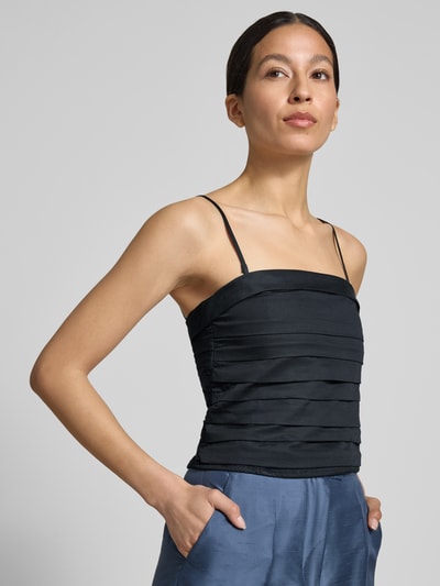 Frauenmodel trägt Bandeau-Top mit abnehmbaren Trägern Modell 'Bella' von My Essential Wardrobe aus reiner Baumwolle, Slim Fit, tiefschwarz, feine horizontale Faltenstruktur, kombiniert mit hellblauer Hose, Ganzkörperansicht von vorne.