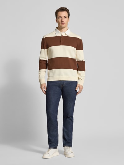 Männermodel trägt Regular Fit Poloshirt mit Streifenmuster von Gant aus reiner Baumwolle, Polokragen, verdeckte Knopfleiste, Ganzkörperansicht von vorne.